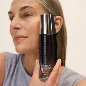 Close up of person holding Cellular Performance Extra Intensive Lotion next to their face with their hand